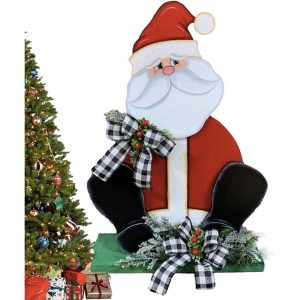 A Christmas Yard Decoration in the form of a solid wood Santa with plaid bows on his shoulder and at his feet