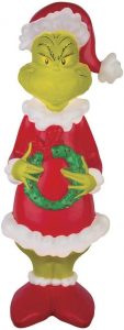 Dr Seuss Grinch in a Santa outfit holding a wreath in both hands
