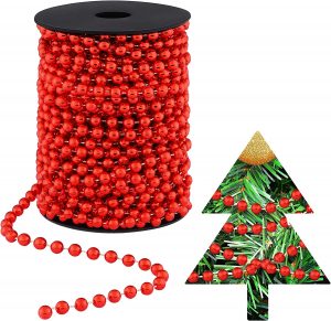 A red beaded garland on a roll with a silhouette of a christmas tree lined with the same