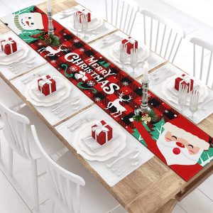A table runner featuring the Stewart Tartan in the middle 3/4 of it with the words Merry Christmas and cartoon pictures of Santa and a snowman on each end