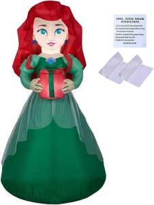 An inflatable Ariel in human form wearing a green dress with her red hair flowing down, holding a red present with a green bow
